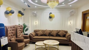 A modern living room with a brown sofa, two round coffee tables, a tufted armchair, and a chandelier.