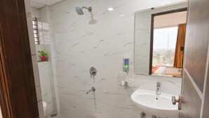 Un baño con ducha, inodoro, lavamanos y un pequeño taburete.