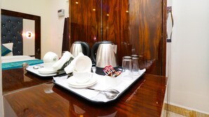 Una habitación de hotel con piso de madera, una cama con cabecera capitonada, una bandeja con alimentos para el desayuno y un espejo que refleja la habitación.