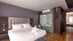 Ein modernes Hotelzimmer mit einem großen Bett, einer Duschkabine aus Glas und Holzboden.