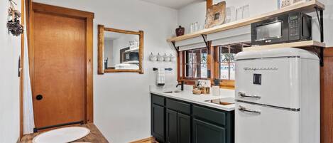 A kitchen with a white refrigerator, wooden cabinets, a wooden countertop, and a hanging light fixture.