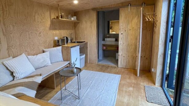 Un interior moderno con techo de madera, un sofá, una mesita y una zona de cocina.