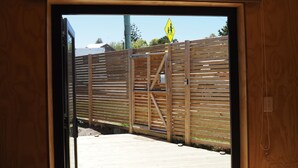 Una verja de madera con una señal amarilla para peatones, una verja metálica y una cubierta de madera.