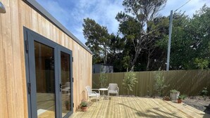 Una terraza de madera con una puerta corrediza de vidrio que da a un patio amueblado al aire libre.