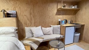 Una habitación compacta con cama, sofá, una pequeña mesa y zona de kitchenette.