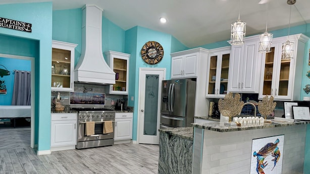 A modern kitchen with white cabinets, a stainless steel refrigerator, and a marble island. - Coastal Comfort Retreat | Near Beach | Sleeps 10! (Rockport)