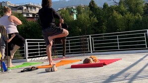 A group of people practicing yoga on an outdoor platform with a view of mountains in the background. - Tranquil trails Naddi Mountain view (Dharamshala)