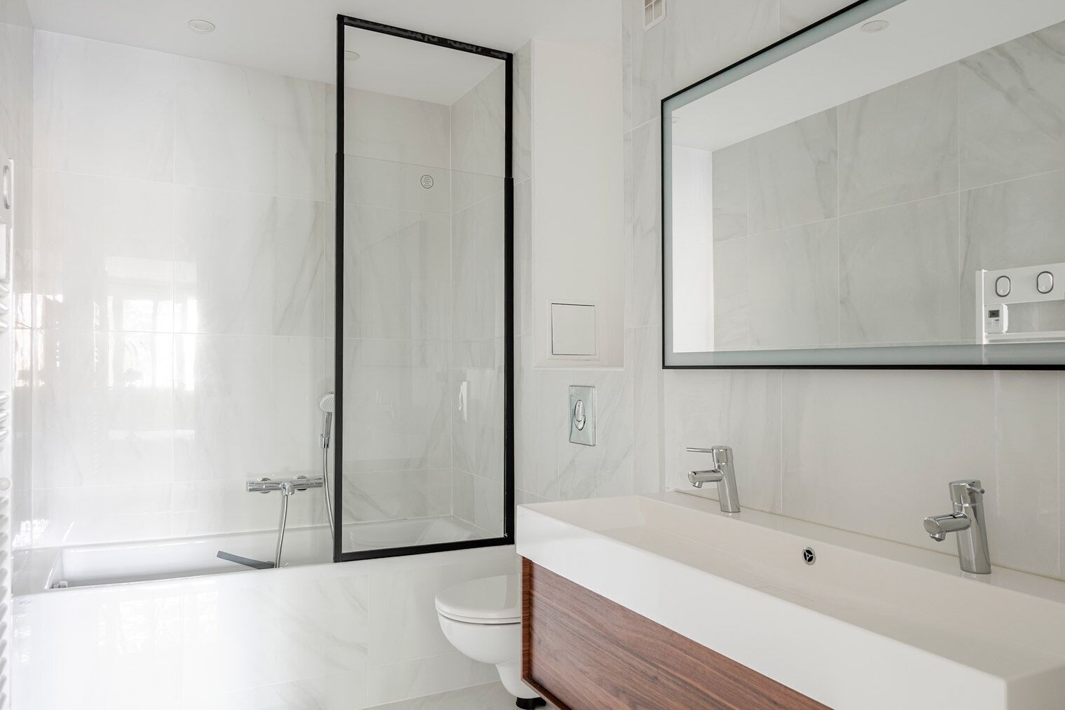 A modern bathroom with a glass-enclosed shower, a toilet, and a vanity with a mirror.