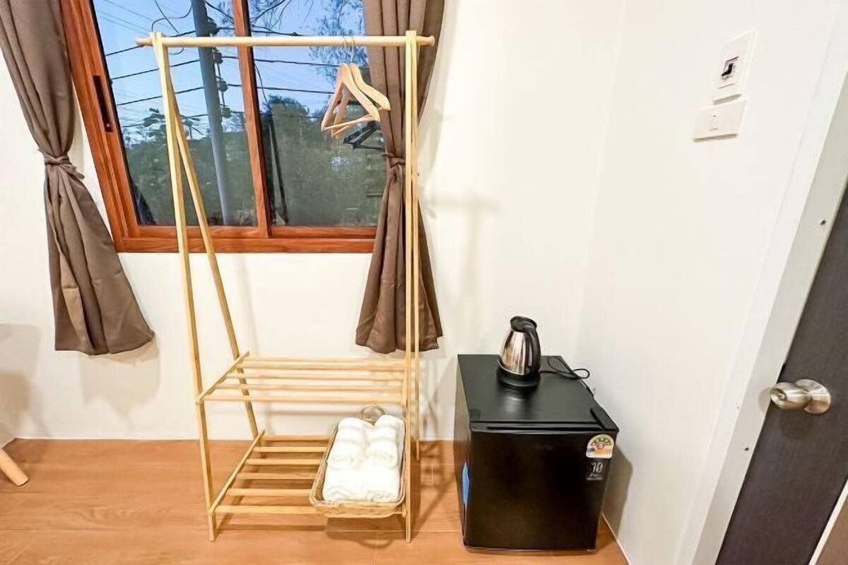 A room with a wooden drying rack, a black coffee machine, and a window with curtains.