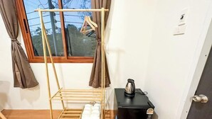 A room with a wooden drying rack, a black coffee machine, and a window with curtains. - Nakai resort Sakon Nakhon (Sakon Nakhon)