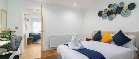 Una habitación de hotel con una cama, un escritorio, una silla, un radiador y un adorno en la pared.
