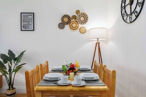 A dining area with a wooden table set for four, surrounded by chairs.