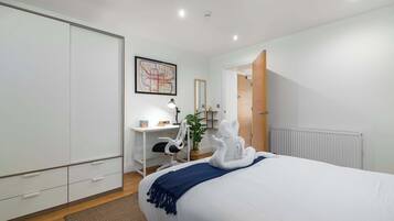 A bedroom with a bed, a desk, a chair, a map on the wall, and a radiator.