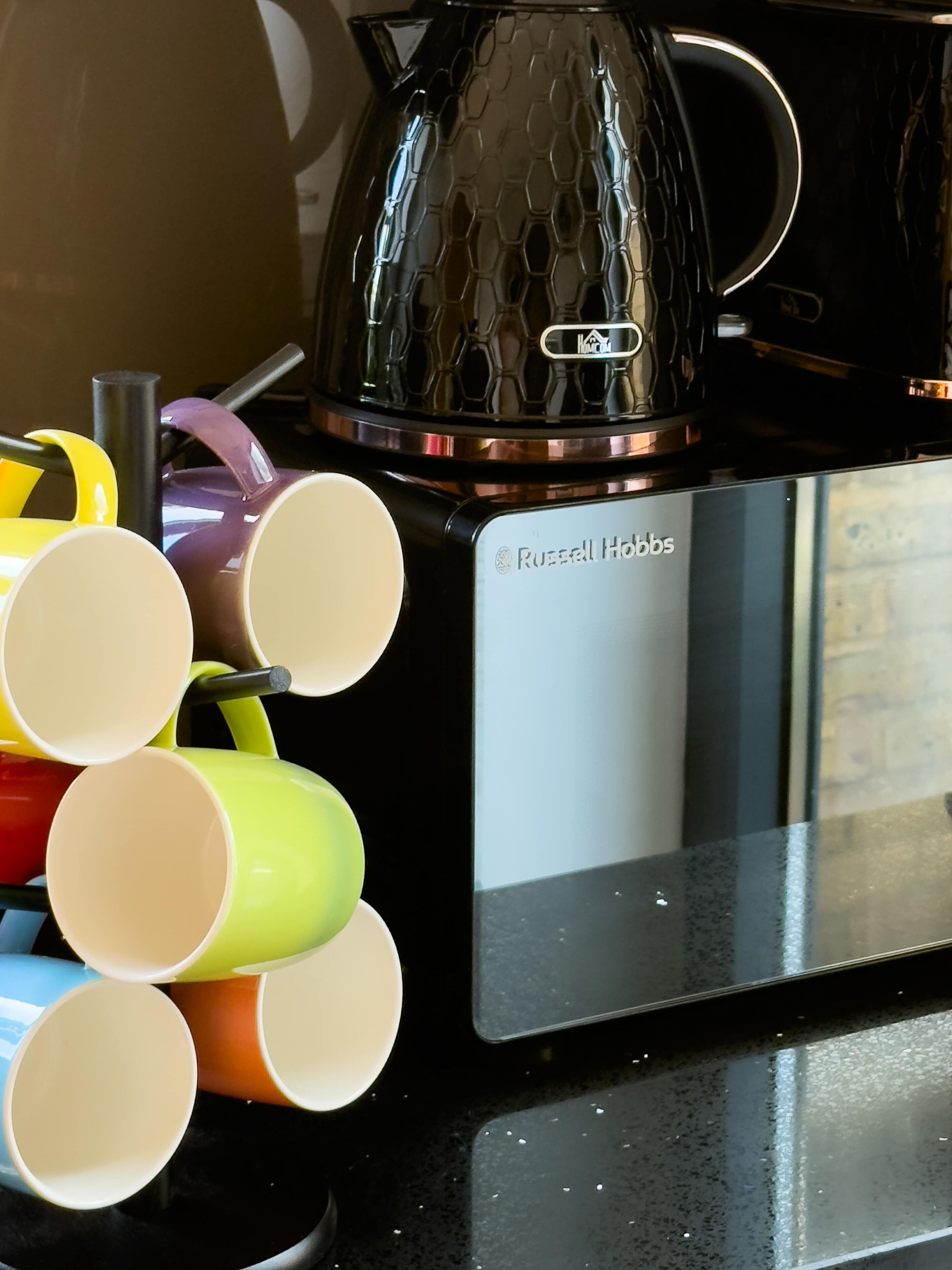 Un área de cocina con cafetera, hervidor y microondas.