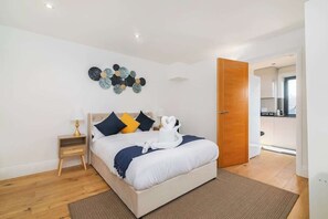 A bedroom with a bed, bedside table, and a wall decoration. - Modern Shoreditch Apartment with Balcony Sleeps 4 (Greater London)