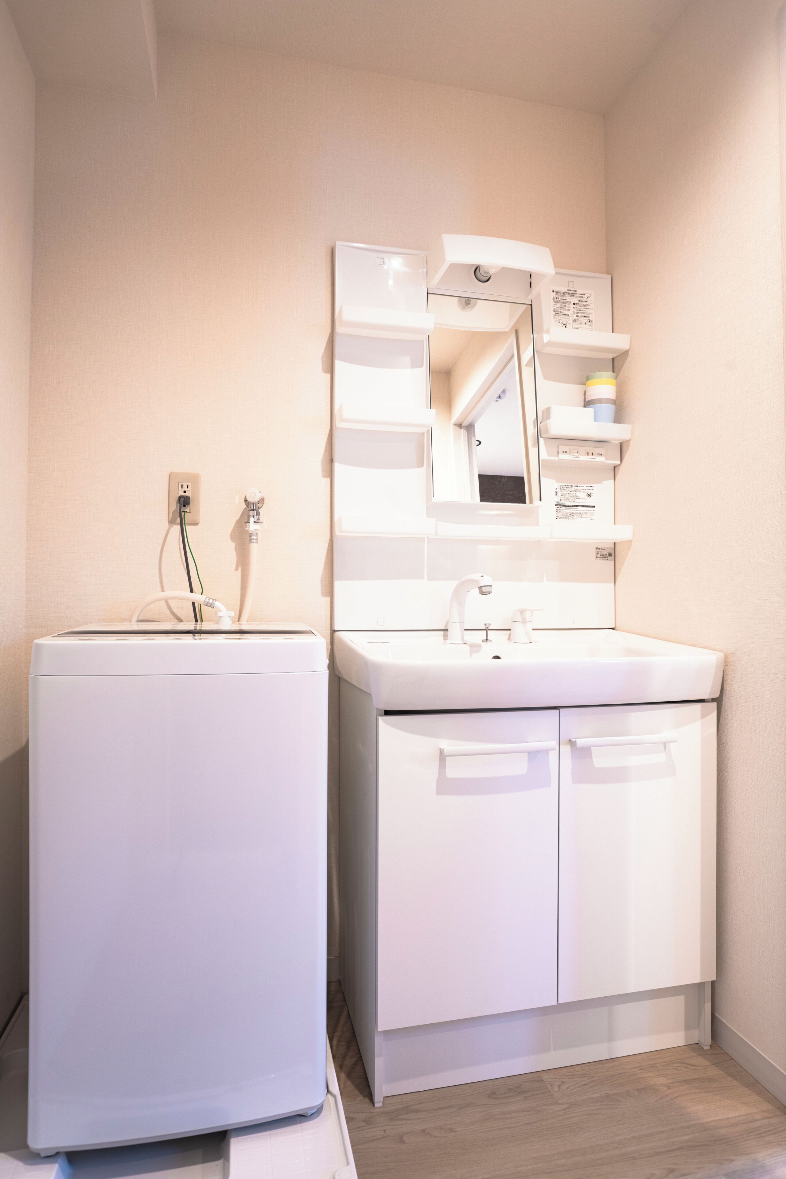 Une salle de bain moderne équipée d’un lave-linge intégré, d’un lavabo et d’un miroir.