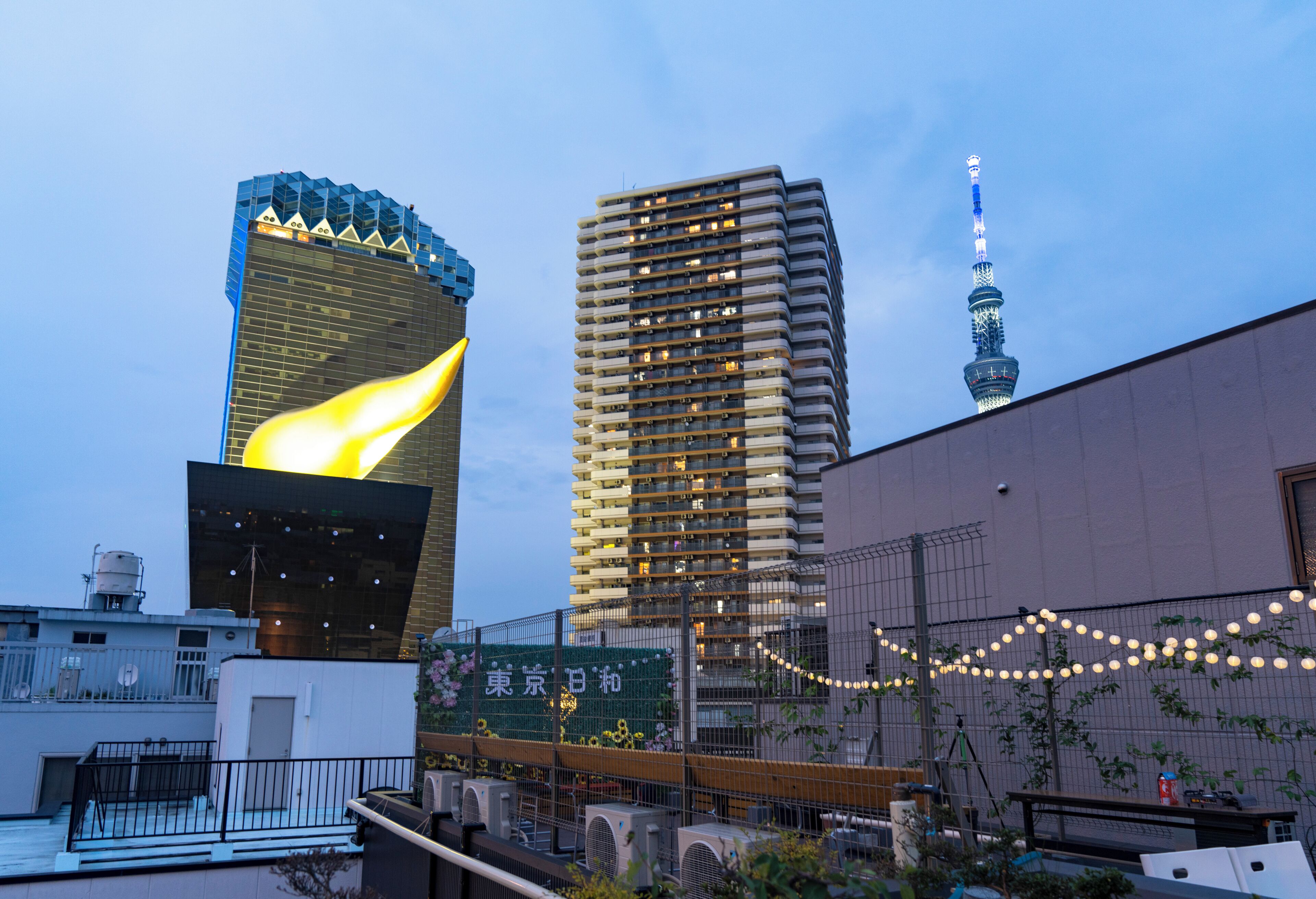 A modern building with a unique flame-like structure on the left, a high-rise building in the center, and a tower with a spire on the right.