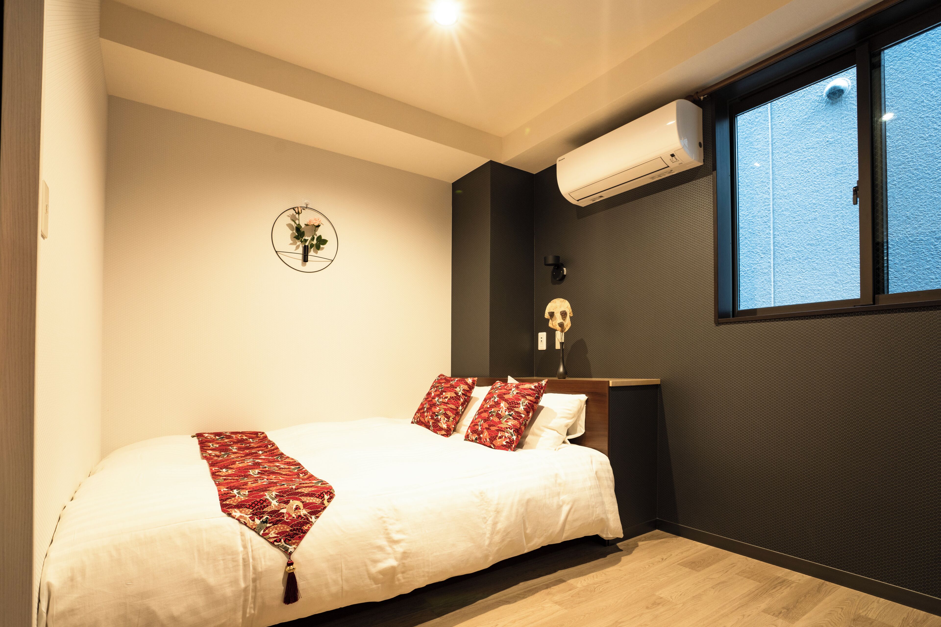 Un dormitorio con cama, aire acondicionado de pared, ventana con vistas y un reloj de pared.