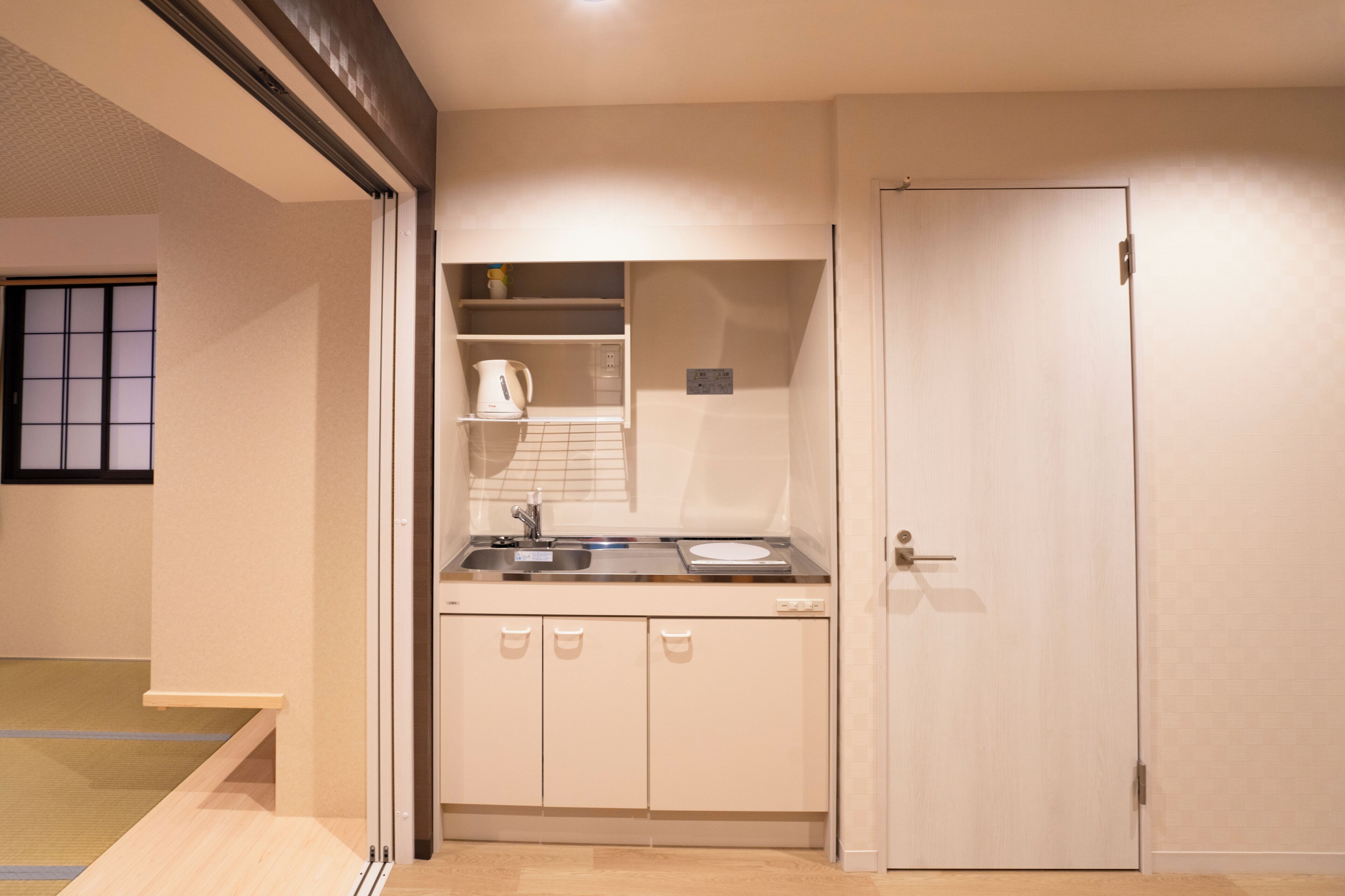 A compact kitchen with a sink, kettle, and cabinets.