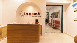 A reception desk with a wooden finish and a potted plant. The wall behind features a sign reading "La Bonté Boutique Home." - La Bonté Boutique Home Phu Quoc (Phu Quoc)