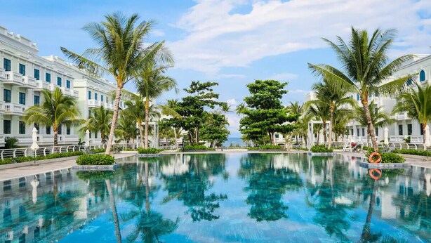 A swimming pool surrounded by palm trees and a building with balconies. - La Bonté Boutique Home Phu Quoc (Phu Quoc)