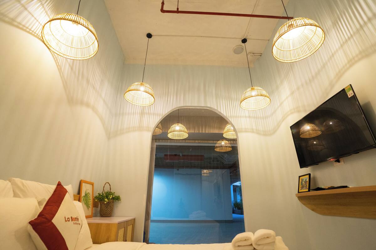 Une chambre d’hôtel avec un lit, une télévision et trois lampes suspendues.