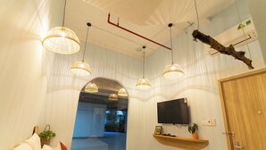 A hotel room with a bed, a TV mounted on the wall, a wooden door, and a view of the outside. - La Bonté Boutique Home Phu Quoc (Phu Quoc)