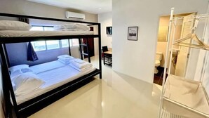 A bunk bed room with a white wall, a desk, and a hanging clothes rack. - Lamoon 90s (Hat Yai)