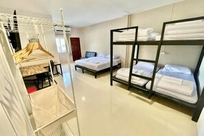 A hotel room with bunk beds, a desk, and a hanging clothes rack. - Lamoon 90s (Hat Yai)