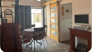 A room with a wooden ceiling, a television on a stand, a table with chairs, and a sliding door leading to an outdoor area. - Charming 1-bedroom cabin in Unidad habitacional Santa Teresa with jacuzzi (Unidad habitacional Santa Teresa)