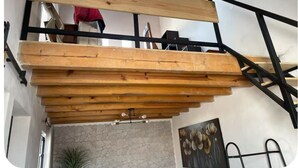A wooden staircase with black metal railings, a stone wall, and a painting of flowers. - Charming 1-bedroom cabin in Unidad habitacional Santa Teresa with jacuzzi (Unidad habitacional Santa Teresa)