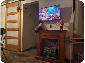 Una sala de estar con chimenea, un televisor montado en la pared y un puerta corrediza.