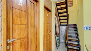 Un pasillo con puertas de madera, una escalera y un tapete rojo en el suelo.