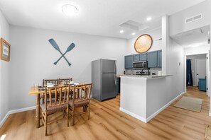 A modern kitchen with a central island, wooden dining table, and chairs.