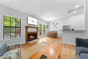 A modern living room with a fireplace, a television, and a dining area.