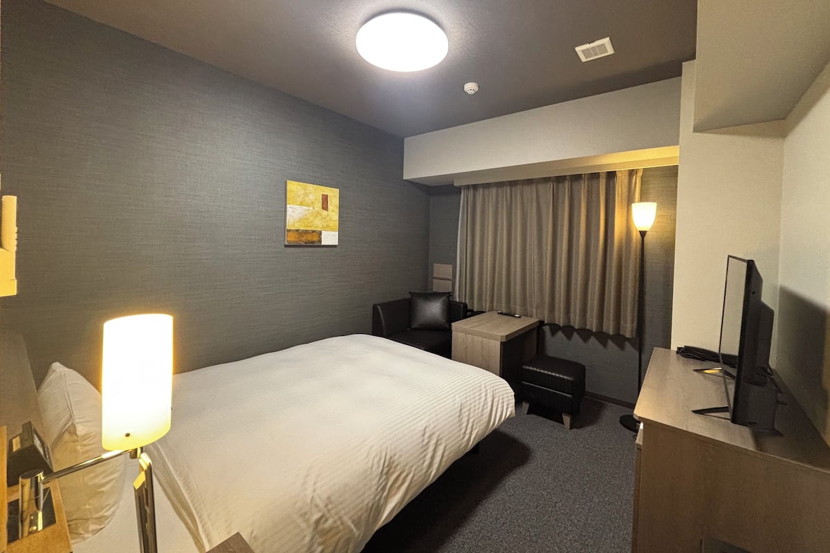 Une chambre d’hôtel équipée d’un lit, d’un bureau, d’une chaise et d’un téléviseur.