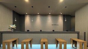 Un área de recepción con una pared de azulejos, un mostrador y bancos de madera.