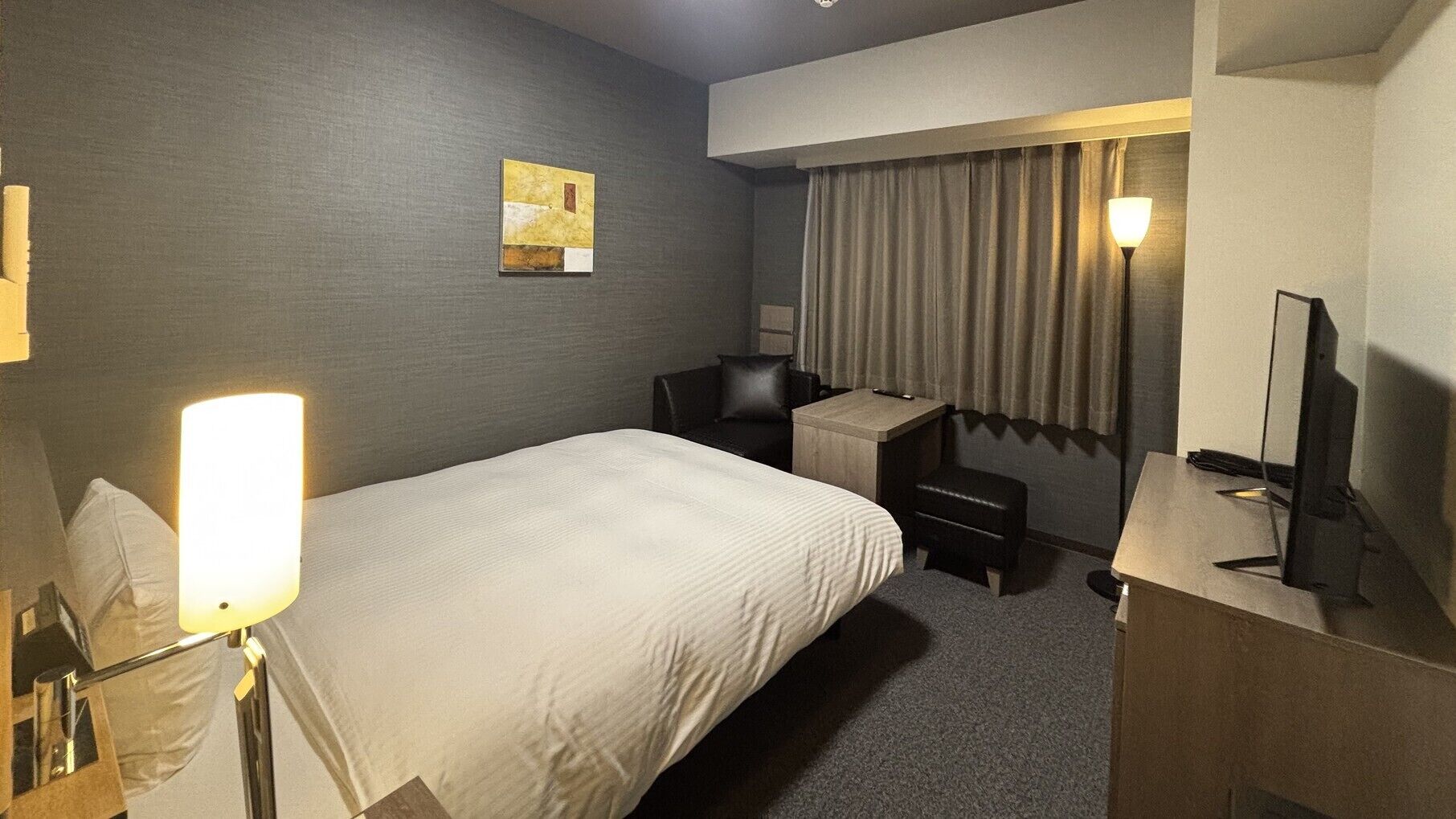 Una habitación de hotel con cama, escritorio, silla y televisor.