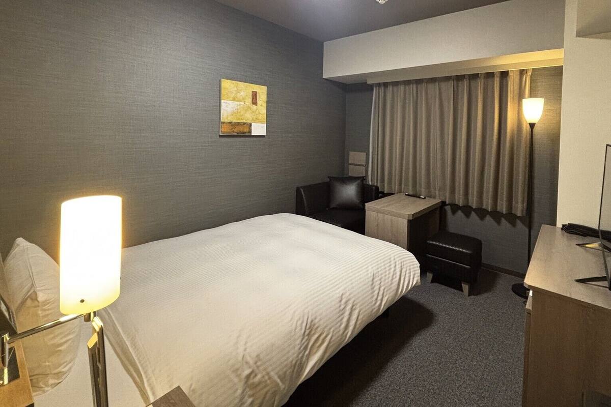Une chambre d’hôtel équipée d’un lit, d’un bureau, d’une chaise et d’un téléviseur.