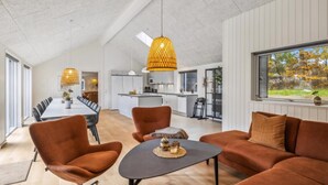Ein geräumiges Wohnzimmer mit hohen Decken, einem Esstisch und modernen Möbeln.