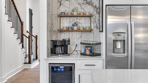 A modern kitchen with a built-in oven, a coffee maker, a water dispenser, and a marble backsplash. - Houston Getaway I Near NRG, Downtown, Airport (Houston)