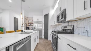 A modern kitchen with white cabinetry, a stainless steel refrigerator, a built-in oven, and a microwave. - Houston Getaway I Near NRG, Downtown, Airport (Houston)