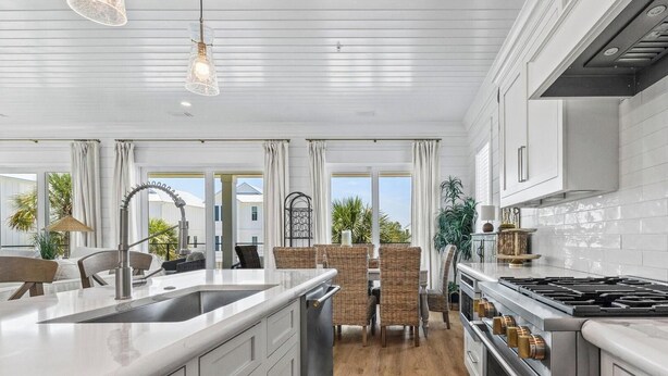 Een moderne keuken met een groot kookeiland, roestvrijstalen apparatuur en uitzicht op de omgeving.