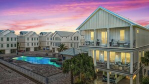 Een resort met meerdere verdiepingen, een zwembad, terras en uitzicht op de ondergaande zon.