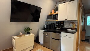 A compact kitchen with a flat-screen TV, a microwave, and a coffee maker. - Cozy 2-bedroom tiny cabin with roomy loft, AC, and fire pit near Bryce Resort (Mount Jackson)