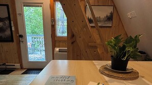 A room with a wooden table, a book titled 'mindful sketching', a potted plant, and a staircase. - Cozy 2-bedroom tiny cabin with roomy loft, AC, and fire pit near Bryce Resort (Mount Jackson)