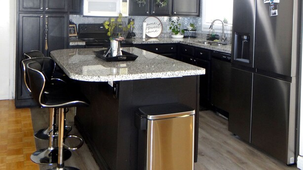 A modern kitchen with dark cabinetry, a stainless steel refrigerator, a built-in microwave, and a granite countertop.