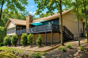 A two-story house with a covered patio, a stone chimney, and a staircase leading to an upper level.