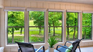 A room with large windows, a potted plant, and two chairs. - Pool House on Ponce De Leon (Hot Springs)