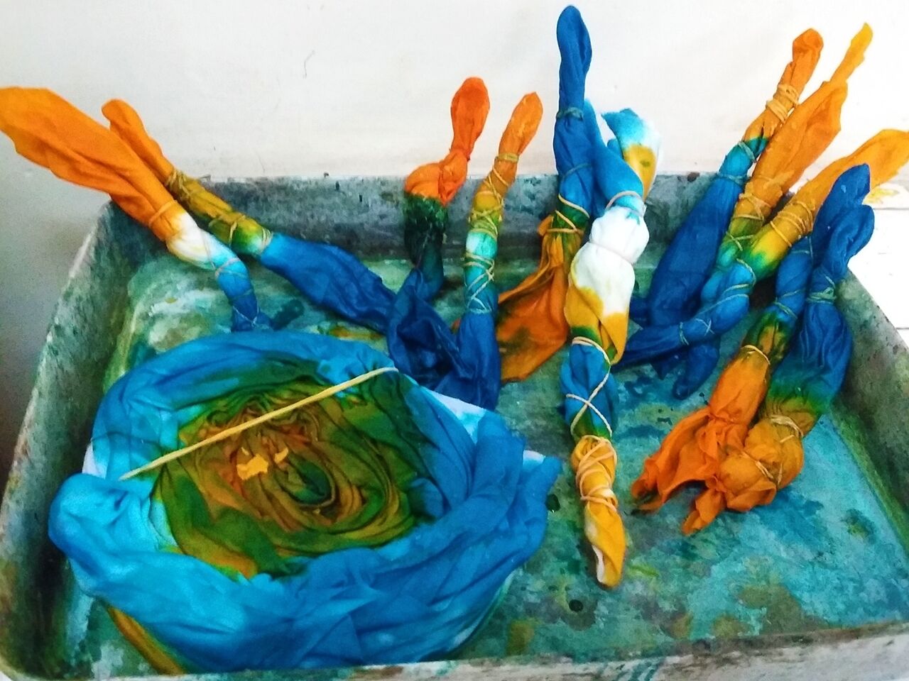 A metal container with several colorful, tied bundles, possibly for storage or display.